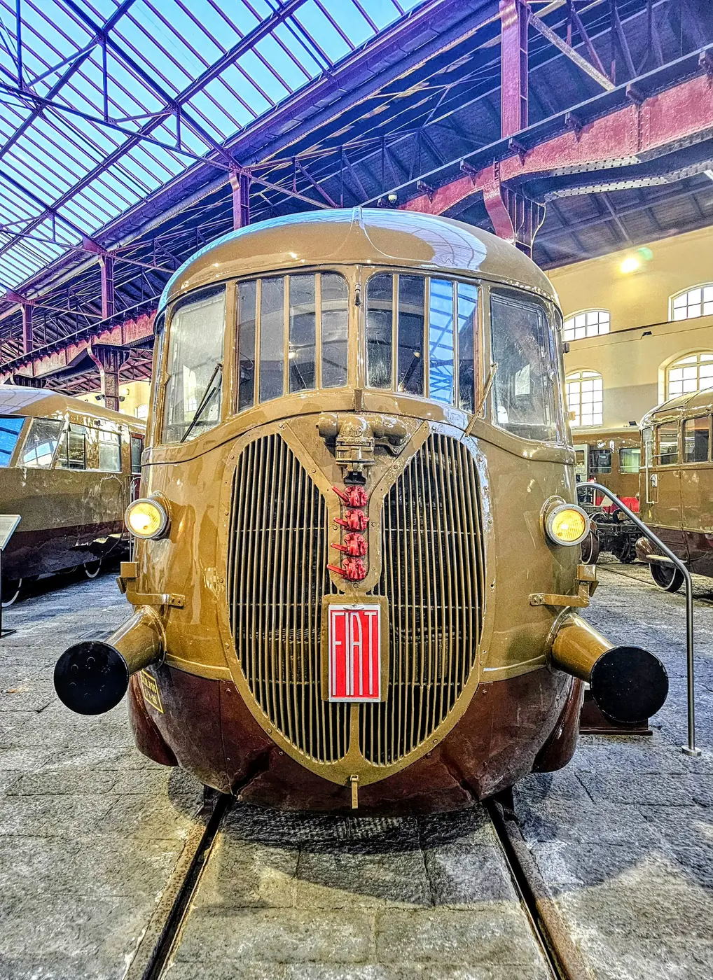 Il muso aerodinamico color bronzo di un treno storico sotto le capriate del Museo nazionale ferroviario di Pietrarsa