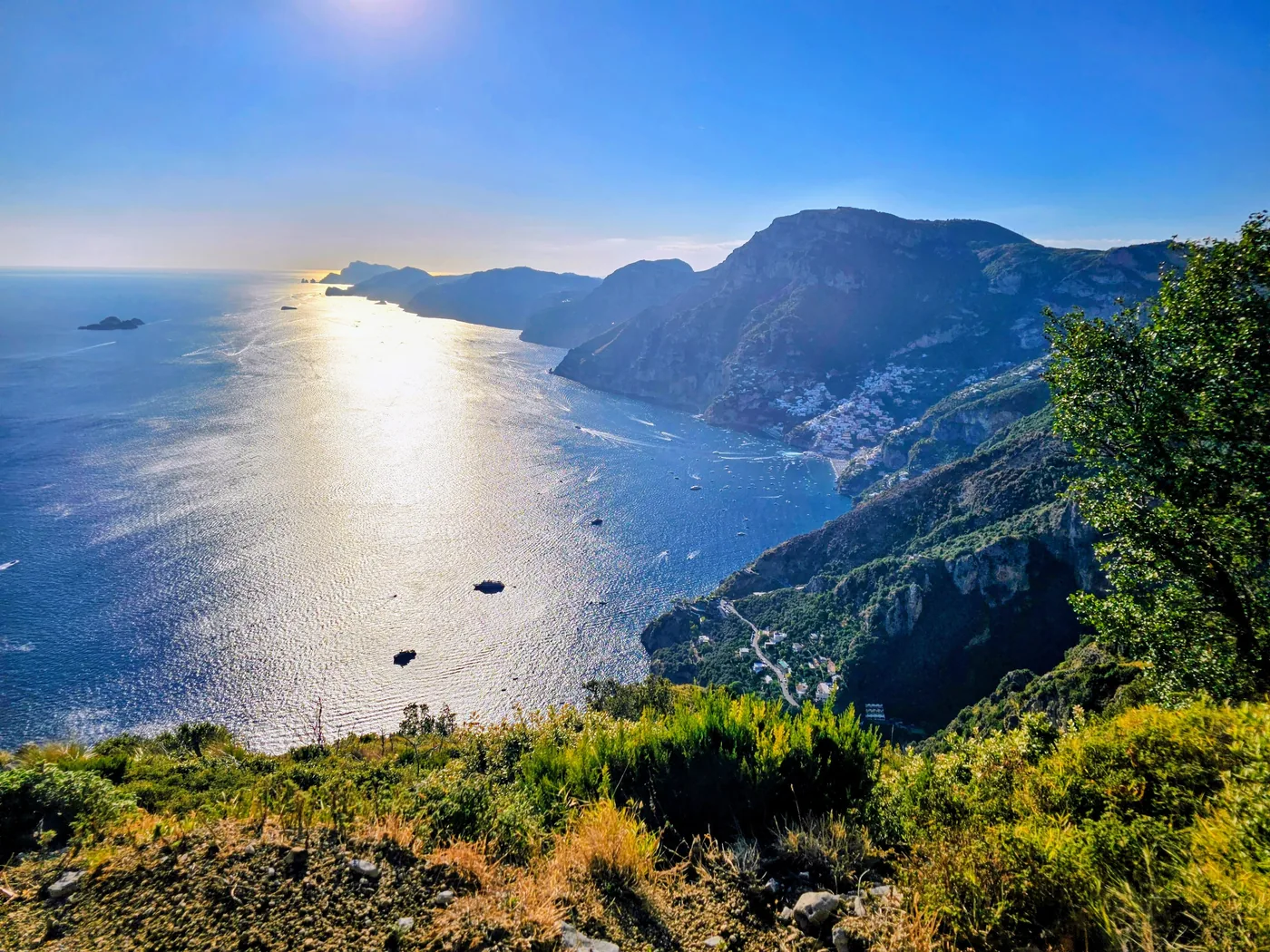 Le case di Positano raccolte nella loro baia, viste dall'alto fra la macchia, con il mare che brilla al sole
