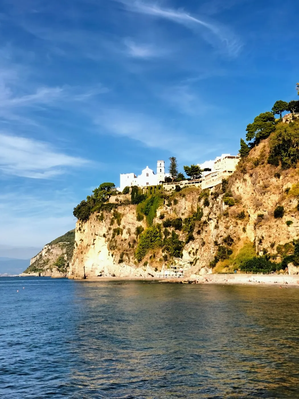 Una falesia chiara a picco sul mare, con le case bianche in cima