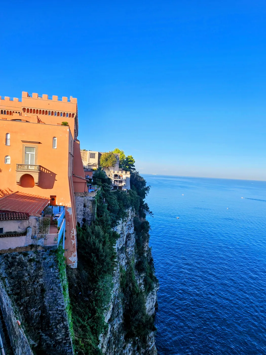 La torre merlata rossa del Castello Giusso sul ciglio della scogliera di Vico Equense, sopra il mare blu