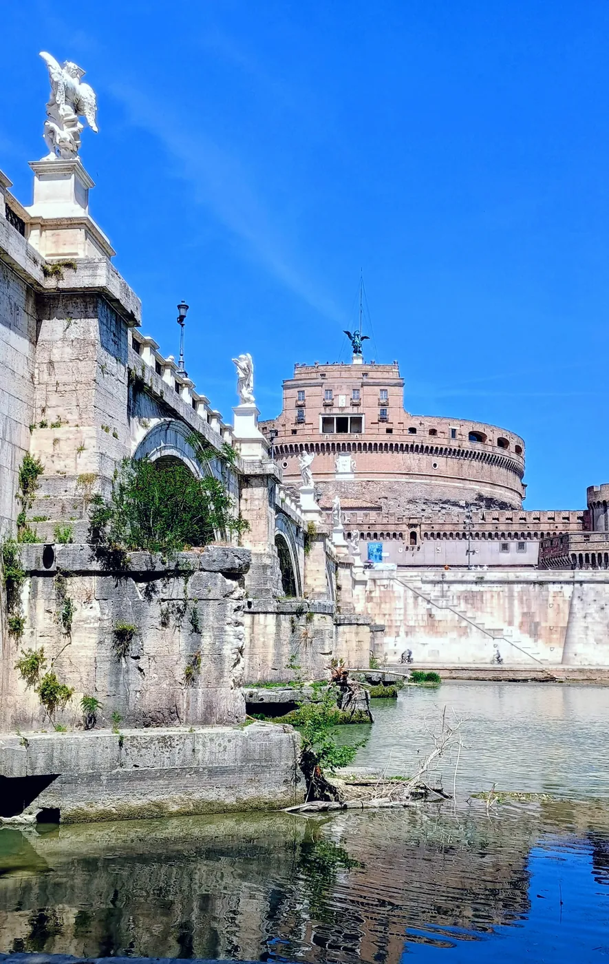 Castel Sant'Angelo e ponte Sant'Angelo con le statue degli angeli, riflessi nel Tevere sotto il cielo azzurro