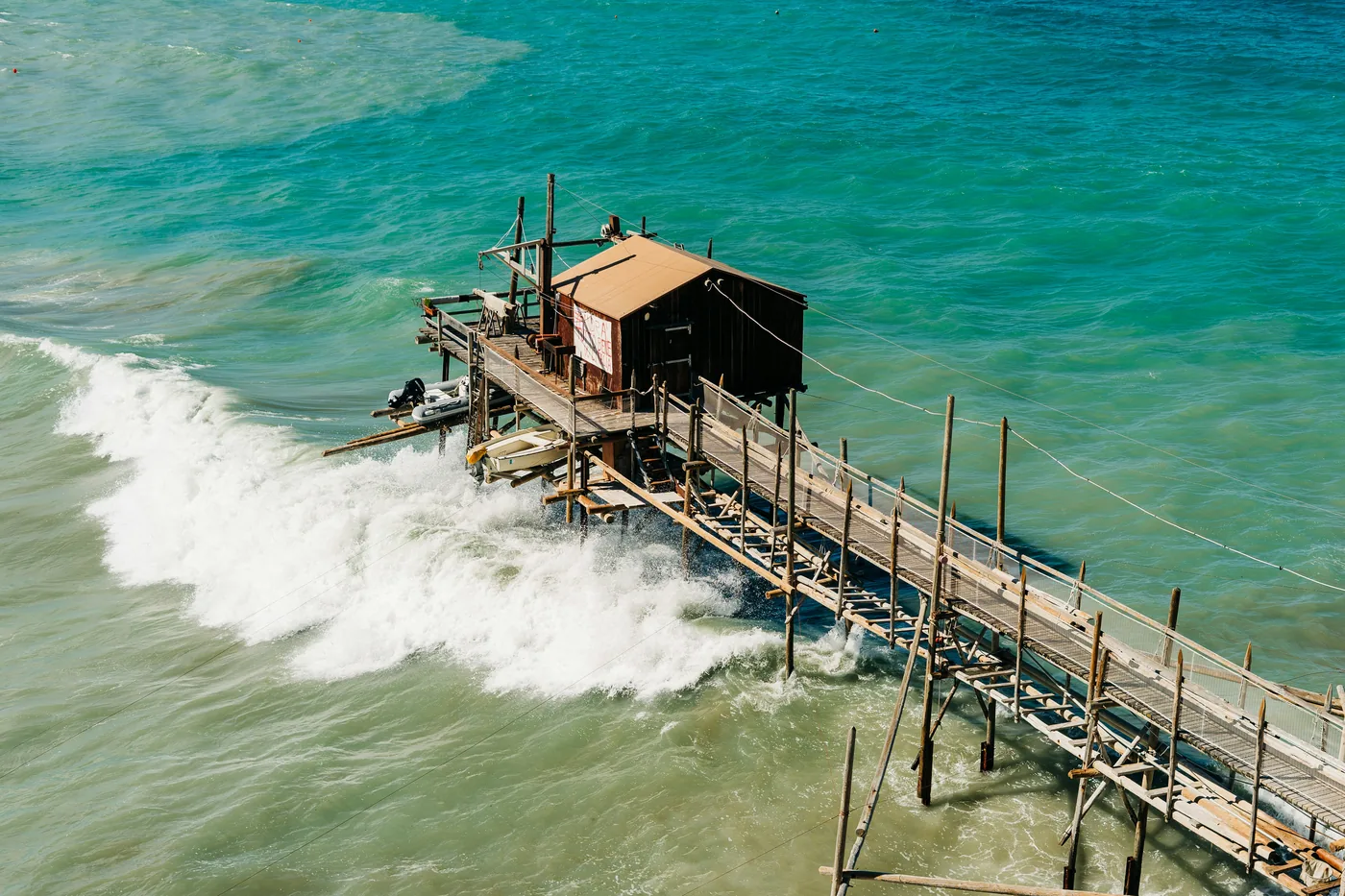 Un trabucco di legno sul mare di Termoli, visto dall'alto mentre un'onda si rompe fra le palafitte